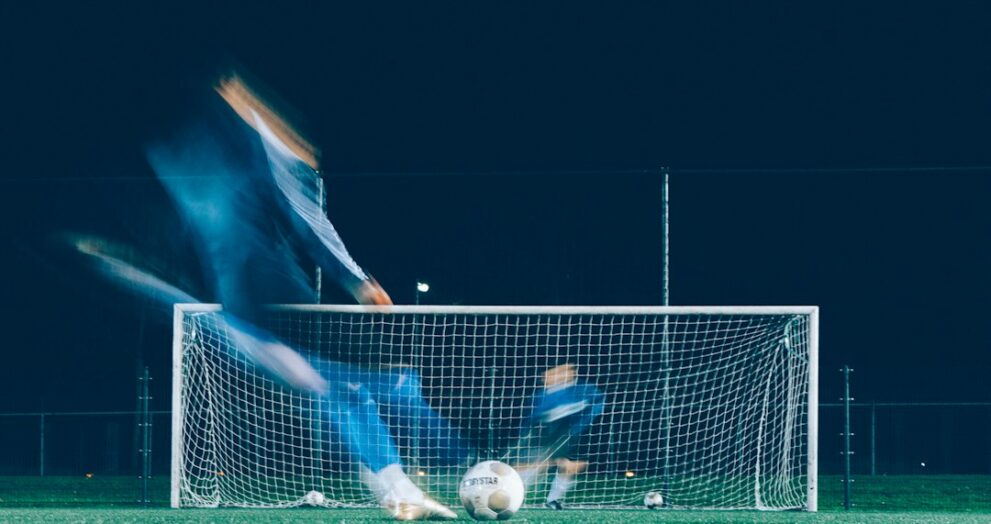 Player shooting at goal as the goalkeeper dives