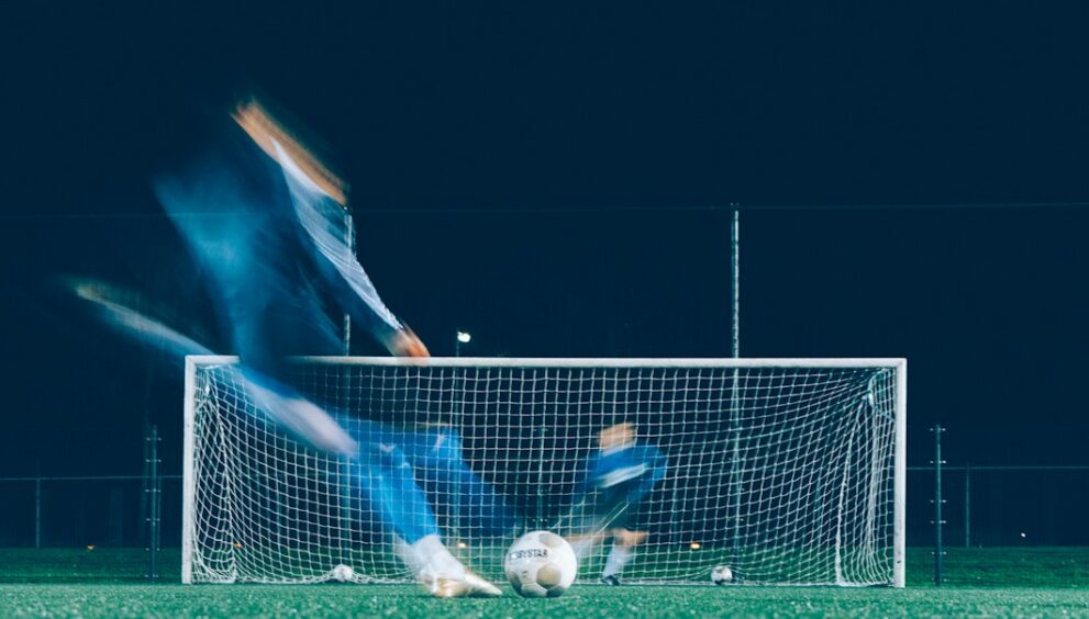Player shooting at goal as the goalkeeper dives