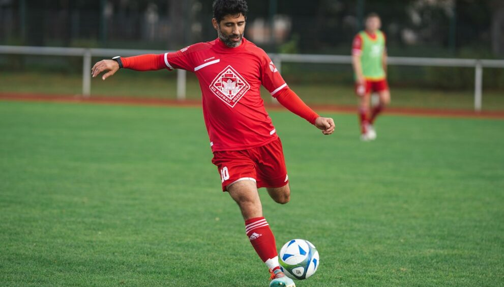 Footballer in a red shirt striking the ball