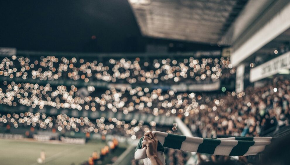 Fan holding up a football shirt in the stands